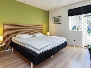 - un grand lit dans une chambre dotée d'un mur vert dans l'établissement Holiday home Ålbæk LXXXVI, à Ålbæk
