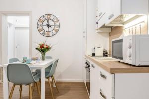 una cocina con mesa y sillas y un reloj en la pared en Donna Teresa Central & Cozy Apartment, en Taranto