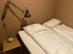 una cama con sábanas blancas y una lámpara sobre una mesa en Oppdal Alpintun, en Oppdal