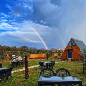 a rainbow over a field with tables and a barn at Yalova Kasaba Bungalov in Çınarcık