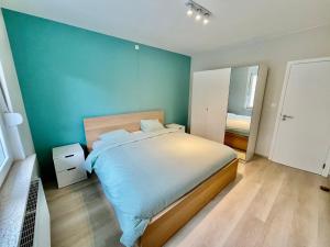 a bedroom with a large bed with a blue wall at Duinenblik 5 in Nieuwpoort