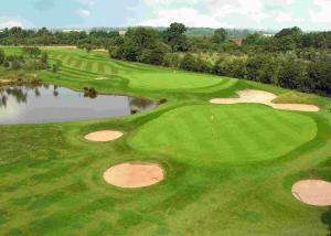 vista aerea su un campo da golf con laghetto di Lea Marston Hotel a Lea Marston