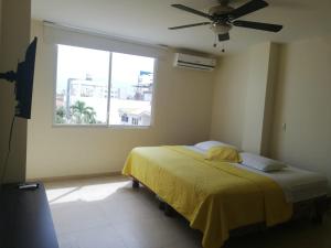sypialnia z łóżkiem z wentylatorem sufitowym i oknem w obiekcie Edificio Galatea w mieście Manta