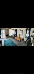 a living room with couches and a blue rug at Luxury Caravan - WI-FI and SMART TV newly installed in Rhyl