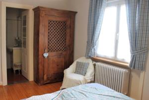 ein Schlafzimmer mit einem Bett, einem Stuhl und einem Fenster in der Unterkunft Aux Berges de la Thur in Staffelfelden