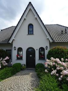 a white house with a black door and flowers at Schönes Ferienhaus in Radewege mit schönem Garten in Radewege
