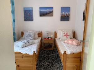 2 Einzelbetten in einem Zimmer mit Bildern an der Wand in der Unterkunft Im Kurpark Hage - Berum in Hage