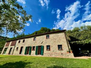 un antiguo edificio de piedra con persianas verdes en un campo de césped en Masseria di Matraia, en Matraia