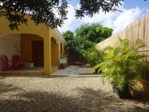 a yellow house with a courtyard with palm trees at Yellow Palms in Kralendijk