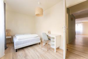 - une chambre blanche avec un lit et un bureau dans l'établissement **Le Classique** - Appartement 40m² à 500m de la Place d'Armes de Douai, à Douai