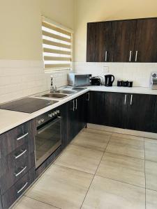 Una cocina con gabinetes de madera y un fregadero. en Ultimate Sky-3 bedroom villa, en Pretoria