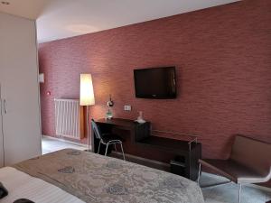 um quarto de hotel com uma secretária e uma televisão na parede em B&B de Taller-Hoeve em Maasmechelen