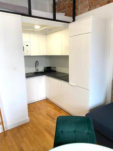 kuchnia z białymi szafkami i zielonym krzesłem w obiekcie Apartament Starówka w mieście Płock