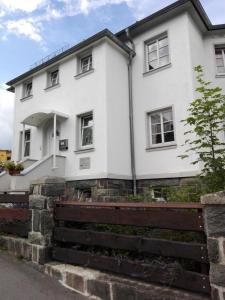 une maison blanche avec une clôture devant elle dans l'établissement Ferienhaus in OberweißbachThüringer Wald mit Grill und Garten, à Oberweißbach