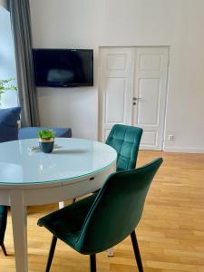stół i 2 zielone krzesła w salonie w obiekcie Apartament Starówka w mieście Płock