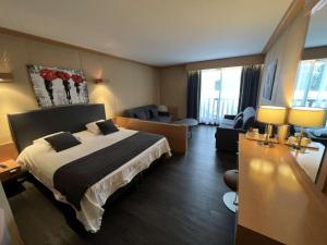 a hotel room with a bed and a living room at Amirauté Hôtel Golf Deauville in Deauville