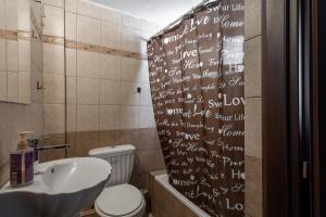 a bathroom with a sink and a toilet with writing on the shower curtain at Beautiful apartment LA in Larisa