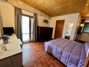 モンテメラノにあるAgriturismo Poggio del Dragoの紫色のベッドとデスクが備わるベッドルーム1室が備わります。
