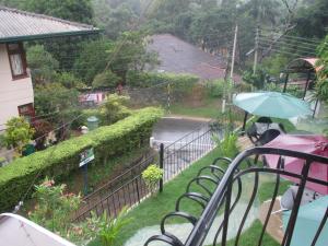 a house with a balcony with an umbrella in the rain at New Kandy Residence in Kandy