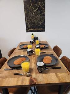 a wooden table with plates of pancakes and glasses of orange juice at BRUSSELS EXPO APARTMENT in Brussels