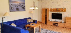 un soggiorno con divano blu e TV di Ferienwohnung-Floppy-Hansi-Fewo-4-EG a Sankt Peter-Ording