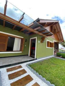 una casa verde con techo de cristal y patio en Casa Petri Gramado en Gramado