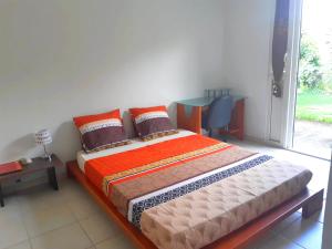 Schlafzimmer mit einem Bett, einem Tisch und einem Fenster in der Unterkunft Chambre privée près des plus belles plages du Nord in La Trinité