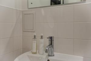 - un lavabo dans la salle de bains avec 2 bouteilles dans l'établissement Central London - The Shoreditch, Angel, Old Street Apartment, à Londres