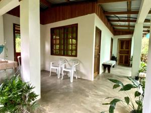 a porch of a house with white chairs and a bench at Casa Briza in Nicoya