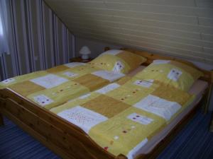 uma cama com uma colcha amarela e branca em Wohnung in Wilhelmsfehn mit Terrasse, Garten und Grill em Wiesmoor