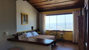 Schlafzimmer mit einem Bett und einem großen Fenster mit Aussicht in der Unterkunft Chales Quinteto de Cores in Lavras Novas