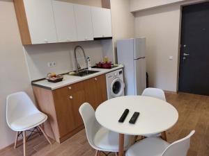 Bakuriani Inn Apartment 13 في باكورياني: مطبخ بطاولة بيضاء وكراسي بيضاء