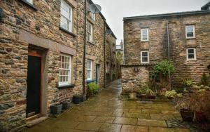 an alleyway between two brick buildings with potted plants at The Folly in Sedbergh