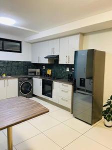 a kitchen with white cabinets and a stainless steel refrigerator at Home away from Home in Windhoek