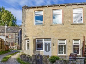 a brick house with a white door on a street at St, Georges Cottage in Holmfirth