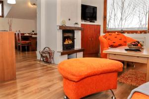 sala de estar con silla naranja y chimenea en Apartmán Ivka en Brezno