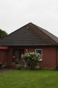 une maison en briques rouges avec une terrasse couverte et un banc dans l'établissement Ferienhaus mit kleinem Garten inklusive Sitzmöglichkeiten und Grill, 