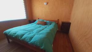 1 cama con edredón azul en una habitación en Cabaña Pellines, en Coñaripe