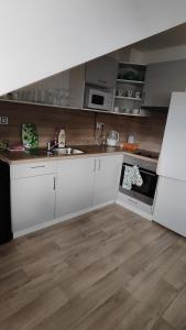 a kitchen with white cabinets and a wooden floor at Apartmán Café u Kordulky in Ratíškovice