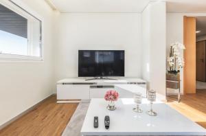 sala de estar blanca con TV y mesa blanca en IsabeLar, en Esposende