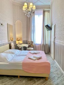 Schlafzimmer mit einem Bett mit einer rosa Decke und einem Kronleuchter in der Unterkunft Hotel Pension Bella in Berlin