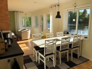 una cocina con mesa blanca y sillas y una habitación en Ferienhaus mit Garten und Holzterrasse direkt am See 