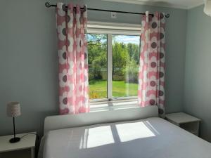 1 dormitorio con 1 cama y una ventana con cortinas en Ferienhaus mit Garten und Holzterrasse direkt am See 