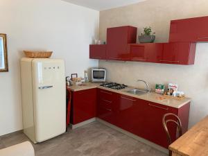 Il comprend une cuisine équipée de placards rouges et d'un réfrigérateur blanc. dans l'établissement PAVIA CENTRO, à Pavia