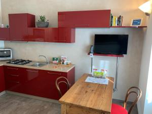 a small kitchen with red cabinets and a wooden table at PAVIA CENTRO in Pavia
