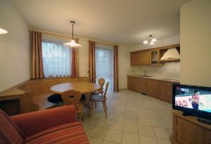 sala de estar con mesa y cocina en Appartamenti Villa Elisa, en Falcade
