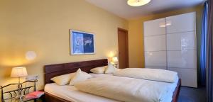 1 dormitorio con 2 camas con sábanas blancas en Ferienwohnungen KUR-ECK en Bad Wörishofen