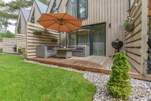 a wooden deck with a table and an umbrella at Vila Una Palanga in Palanga