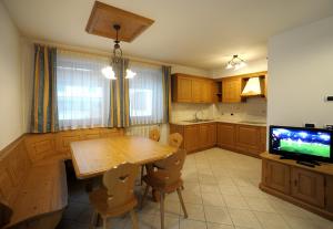 cocina con mesa de madera y TV en Appartamenti Villa Elisa, en Falcade