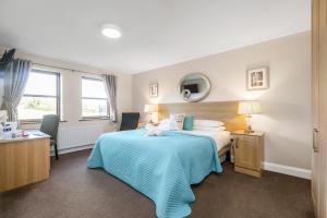 Tollyrose Country House في نيوكاسل: غرفة فندق بسرير وبطانية زرقاء